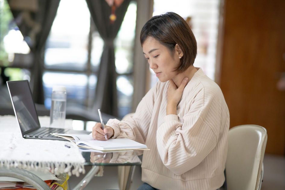 中国系の女性が自宅で仕事をしながら体調に気をつける様子