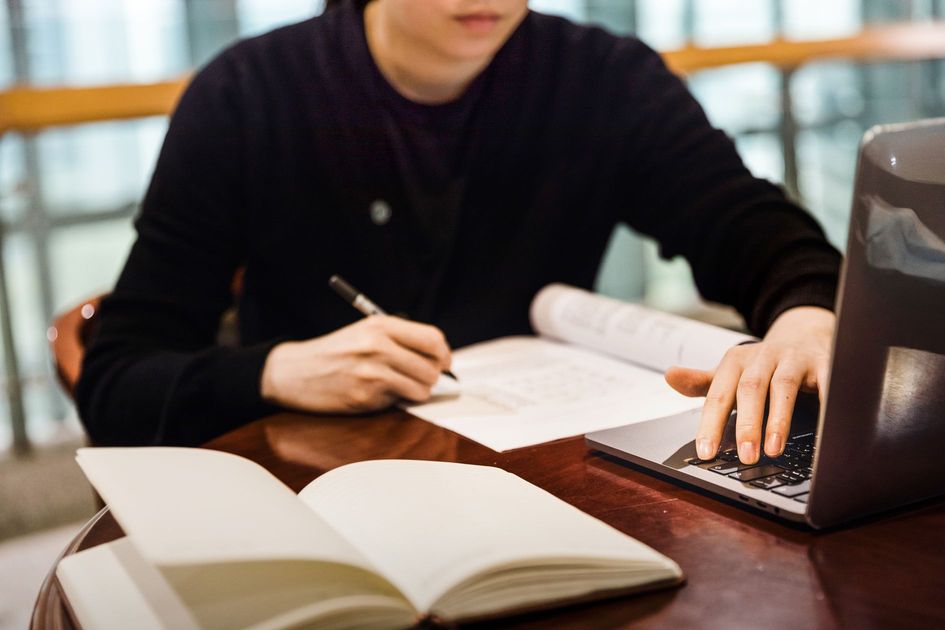 HTMLの基本概念を学ぶため、パソコンでコードを確認する若い女性の姿を捉えた画像。